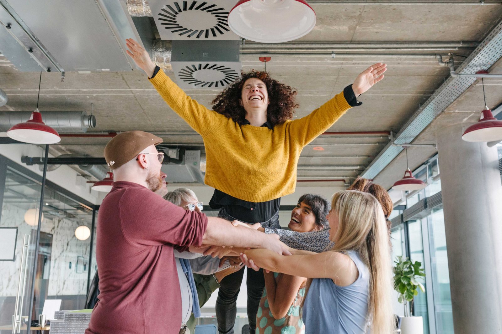 Image depicts a team building exercise in a work environment - one person falling into the arms of her colleagues. Trust fall exercise...