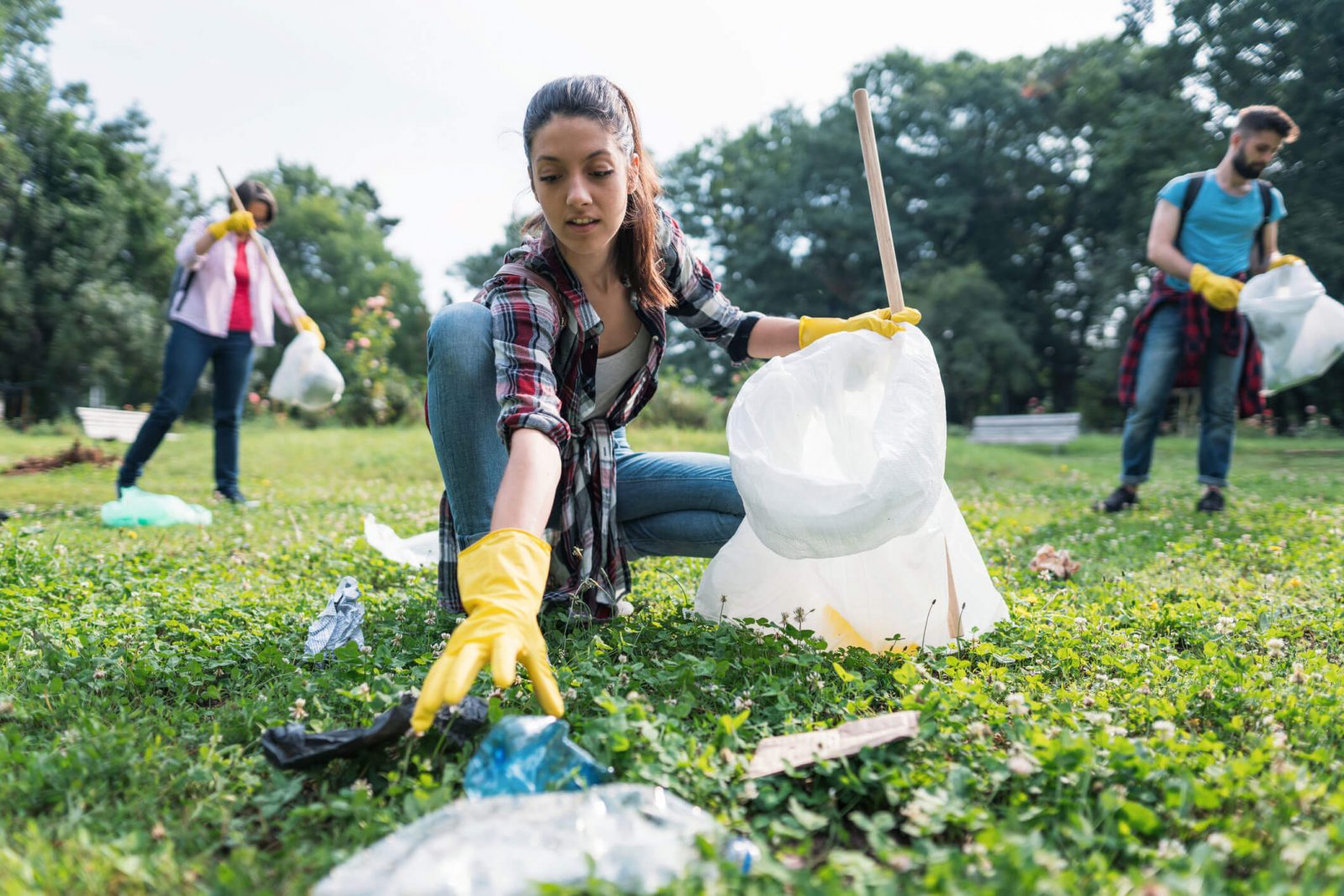 Young woman picking up litter thrown away in the park