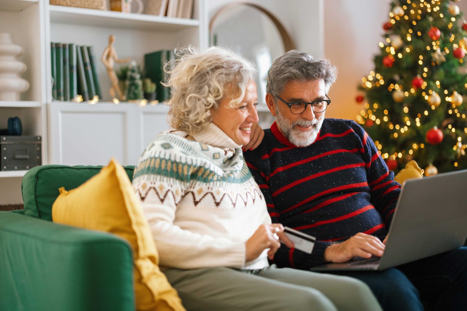 Mature couple shopping online for Christmas gifts at home